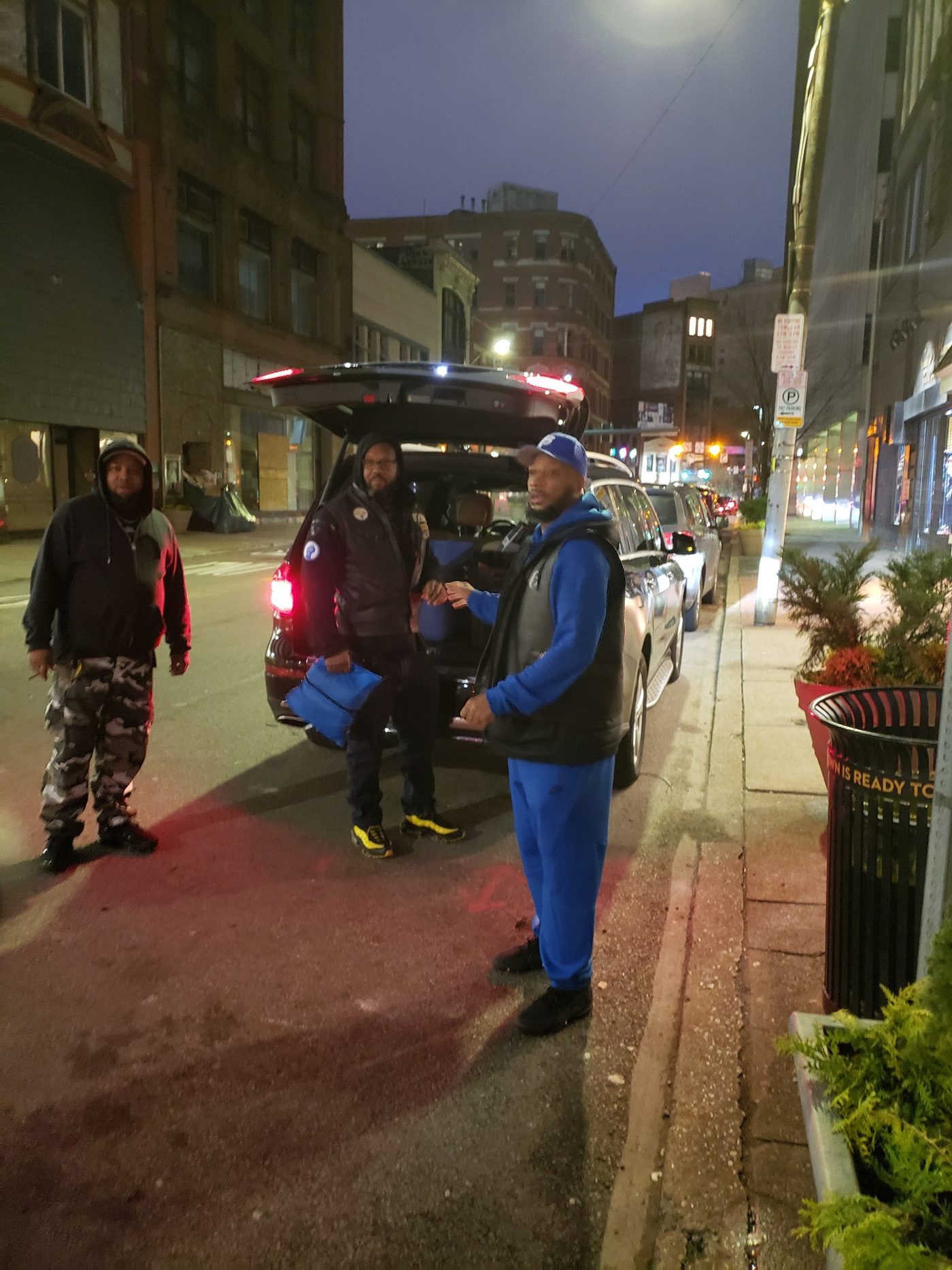 Volunteers unloading supplies from a car on a downtown street